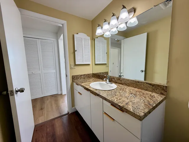 a bathroom with a granite countertop sink a large mirror and a shower