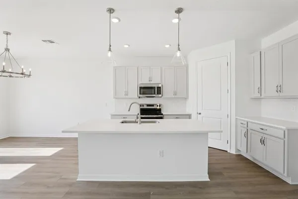 a kitchen with stainless steel appliances granite countertop a stove a sink and a refrigerator with wooden floor