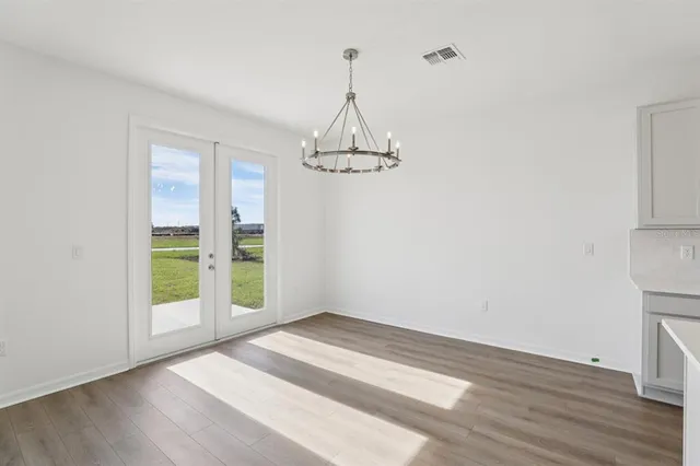 a kitchen with stainless steel appliances granite countertop a stove a sink a refrigerator and white cabinets with wooden floor