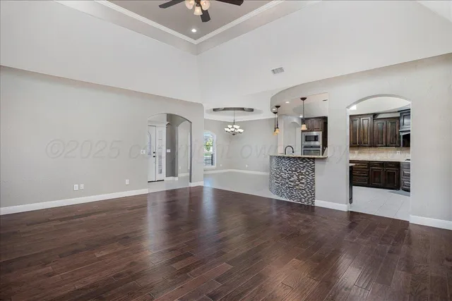 a view of an empty room with a kitchen and wooden floor