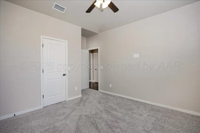 an empty room with chandelier fan and windows