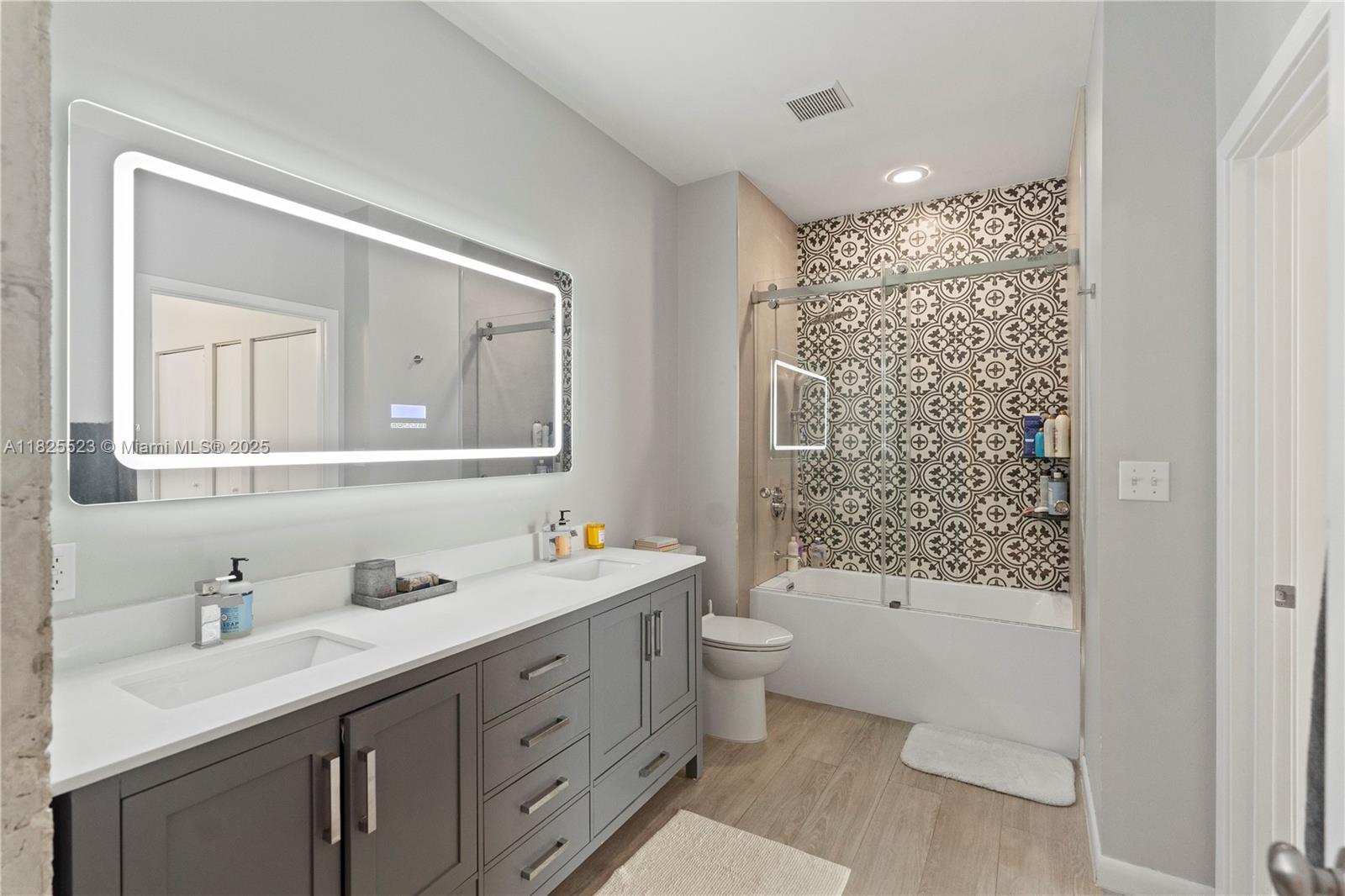 2001 Biscayne Boulevard, Unit 2201 Miami, FL 33137 - Photo 16 of 42 a bathroom with a double vanity sink toilet mirror and bathtub