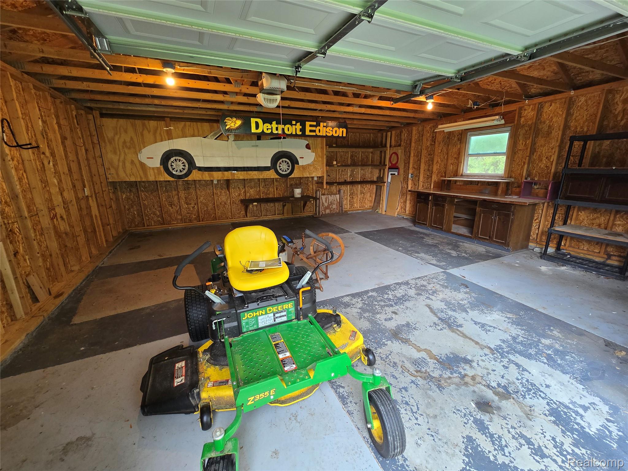 5282 McIntyre Road North Street, MI 48049 - Photo 52 of 53 Spacious garage featuring exposed wood framing, concrete flooring, built-in workbench with cabinetry, and an overhead garage door
