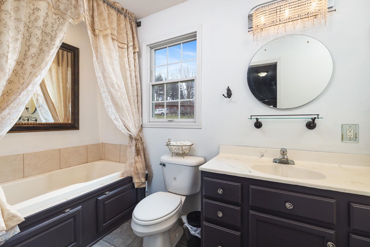 1011 North Dakota Road Ridott, IL 61067 - Photo 19 of 34 a bathroom with a sink a mirror a toilet and a bathtub