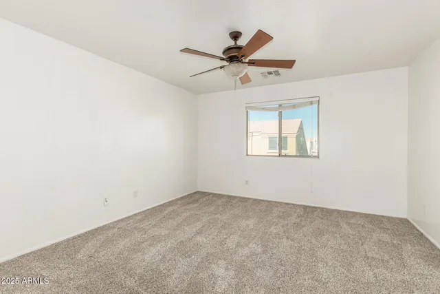 an empty room with a window and a fan