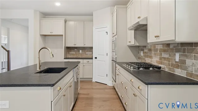 a kitchen with granite countertop a sink stove and cabinets