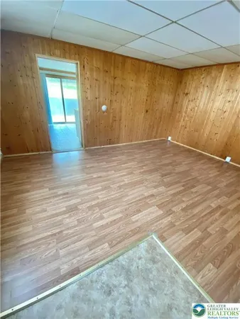 an empty room with wooden floor and windows with curtains