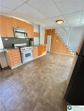 a large kitchen with stainless steel appliances a sink a stove top oven a counter space and cabinets