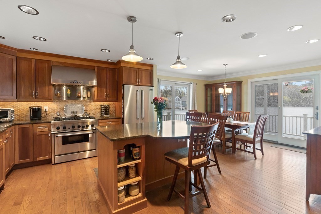 4 Birchmeadow Road Amesbury, MA 01913 - Photo 7 of 42 a kitchen with stainless steel appliances granite countertop a stove top oven a refrigerator a dining table and chairs with wooden floor