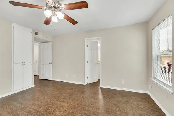 an empty room with windows and fan