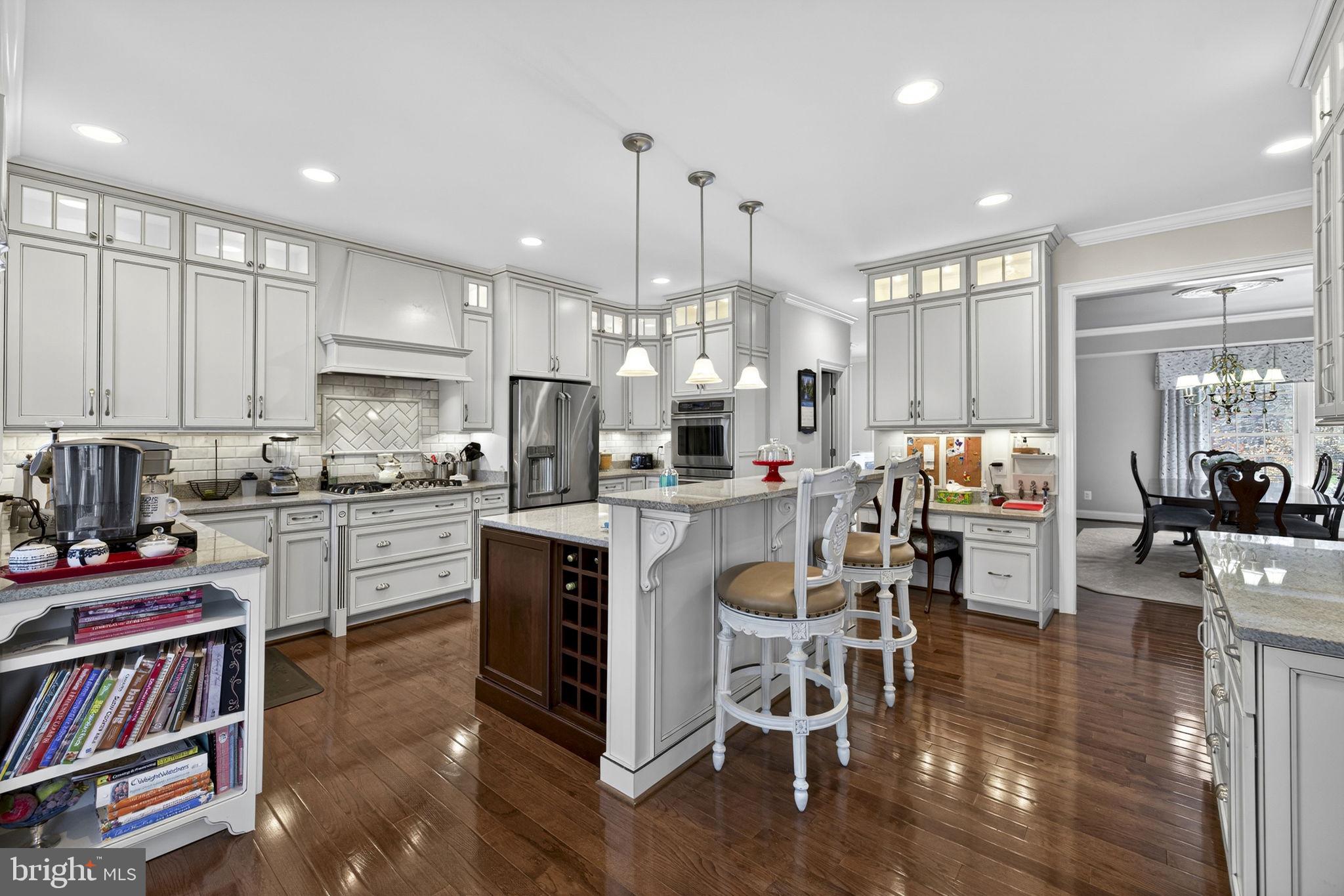 8485 Rogues Road Warrenton, VA 20187 - Photo 12 of 121 a kitchen with stainless steel appliances granite countertop a stove top oven a sink dishwasher and a dining table with wooden floor