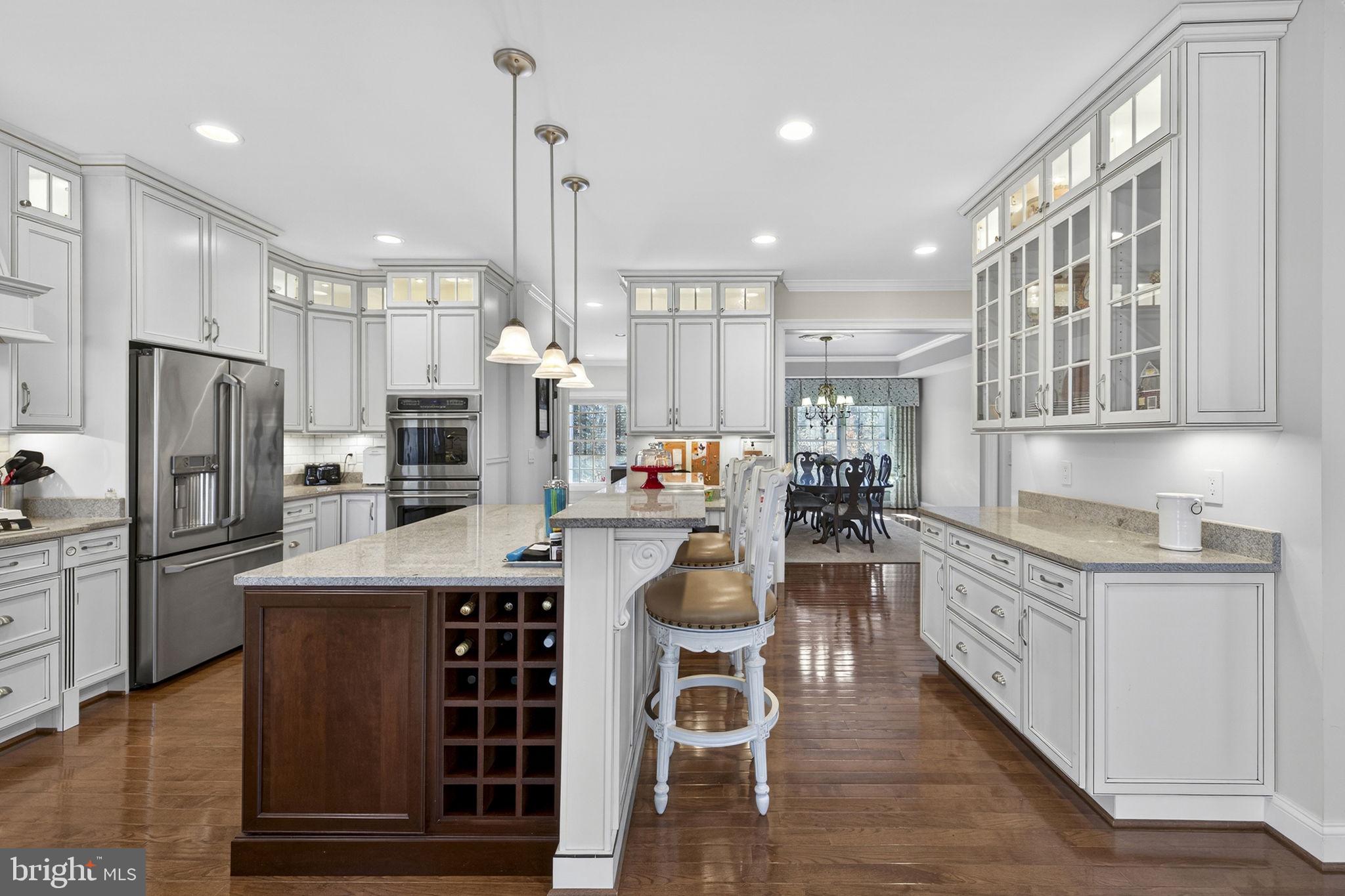 8485 Rogues Road Warrenton, VA 20187 - Photo 14 of 121 a kitchen with stainless steel appliances kitchen island granite countertop a refrigerator oven a sink a dining table and chairs with wooden floor