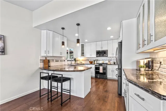 a kitchen with stainless steel appliances kitchen island granite countertop a table chairs microwave and cabinets