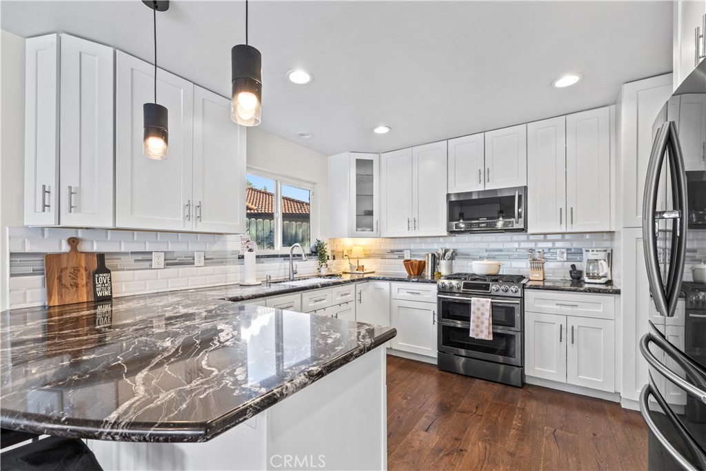 28046 Millar Street Highland, CA 92346 - Photo 11 of 39 a kitchen with stainless steel appliances granite countertop a stove top oven a sink a refrigerator and white cabinets with wooden floor