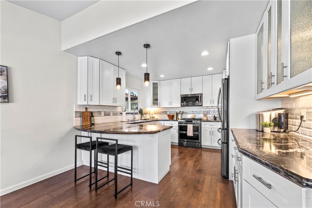 28046 Millar Street Highland, CA 92346 - Photo 8 of 39 a kitchen with stainless steel appliances kitchen island granite countertop a table chairs microwave and cabinets