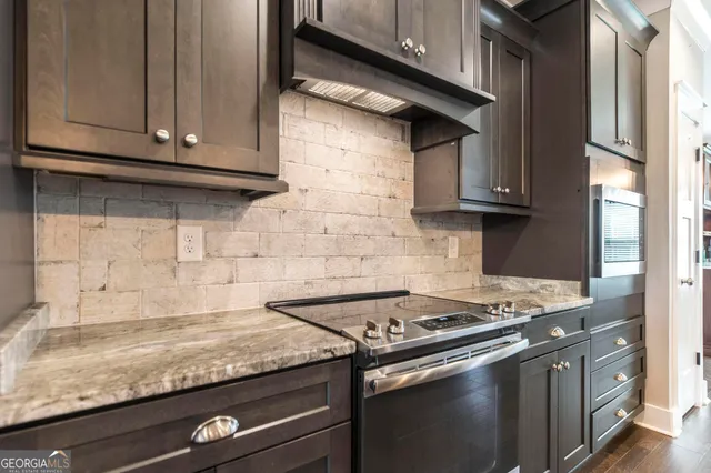a kitchen with granite countertop cabinets stove top oven and microwave