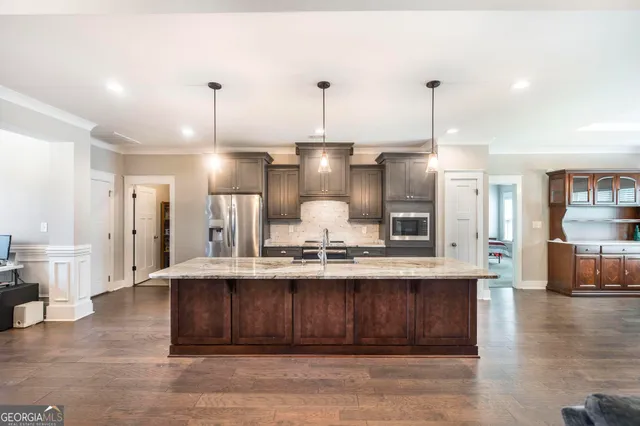 a view of a kitchen with kitchen island a sink stainless steel appliances and cabinets