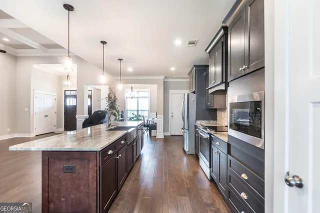 a large kitchen with stainless steel appliances granite countertop a lot of counter space and a sink