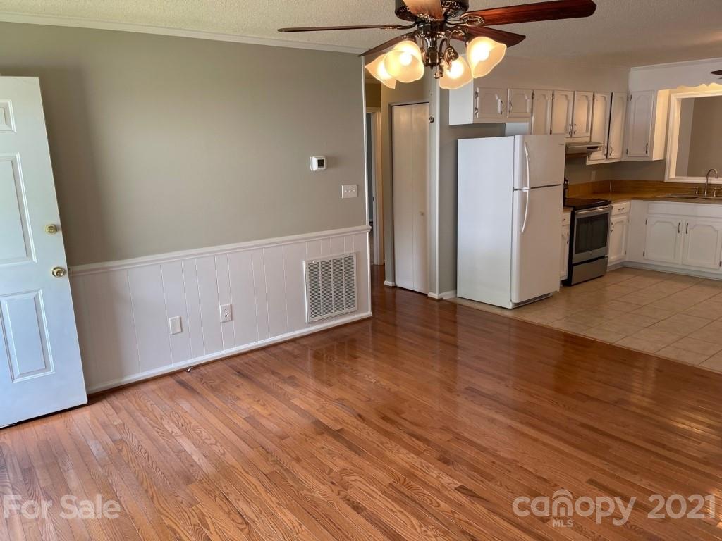 129 Loray Farm Road Dallas, NC 28034 - Photo 12 of 28 an empty room with wooden floor cabinet and a kitchen view
