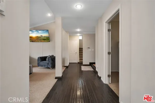 a view of a hallway with wooden floor and a bathroom