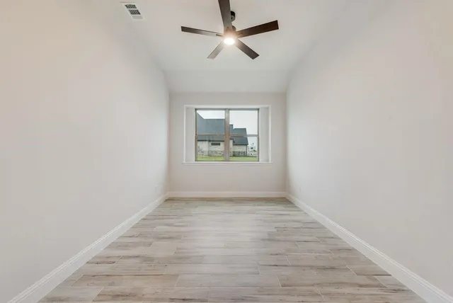 an empty room with windows and fan