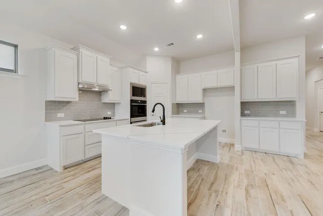 a kitchen with white cabinets stainless steel appliances and sink