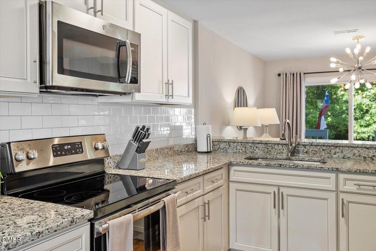 8321 Hempshire Place, Unit 103 Raleigh, NC 27613 - Photo 9 of 25 a kitchen with stainless steel appliances granite countertop a stove microwave and cabinets