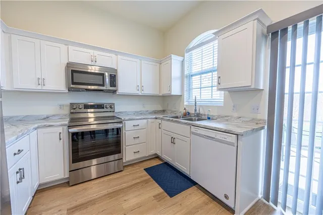 a kitchen with stainless steel appliances granite countertop a stove a sink and a microwave