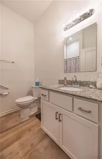 a bathroom with a granite countertop toilet sink and mirror