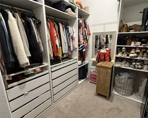 a view of walk in closet with clothes and shoes