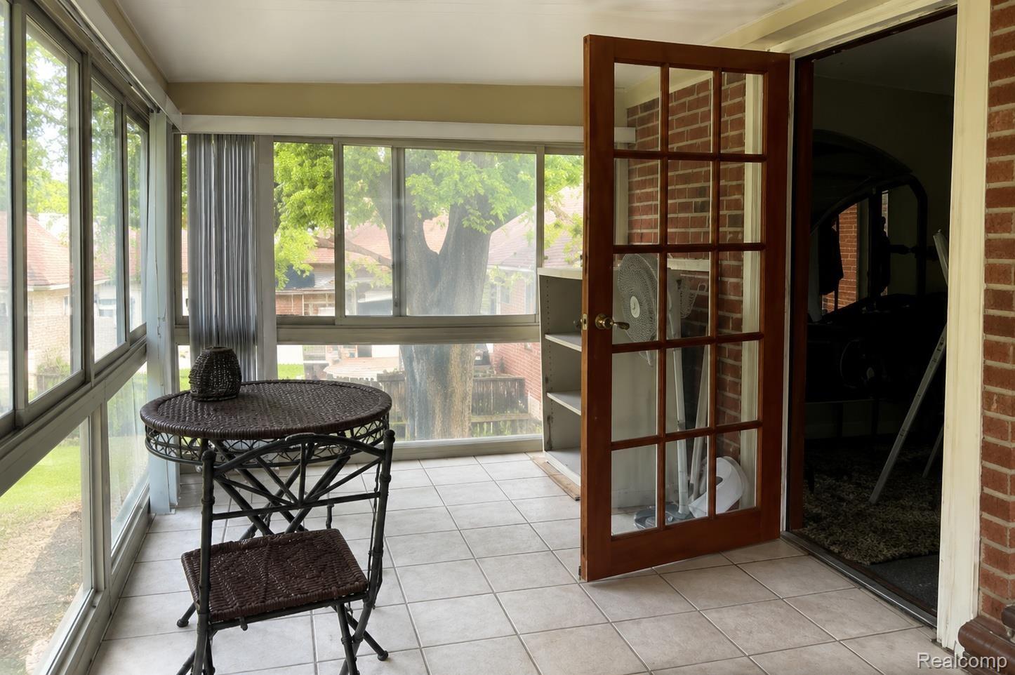 9552 Wayne Road Livonia, MI 48150 - Photo 15 of 31 Spacious second-floor three-season room with walls of windows, tile flooring, and peaceful backyard views, creating a bright and relaxing extension of the upper-level bedroom suite.