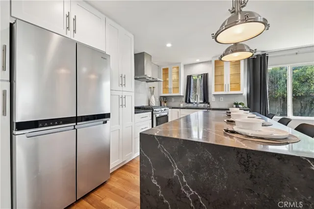 a kitchen with stainless steel appliances kitchen island granite countertop a stove a sink a dining table and chairs with wooden floor