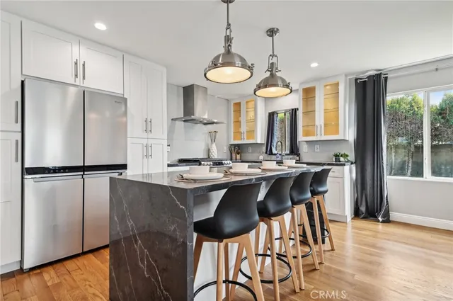 a kitchen with stainless steel appliances a table chairs refrigerator and cabinets