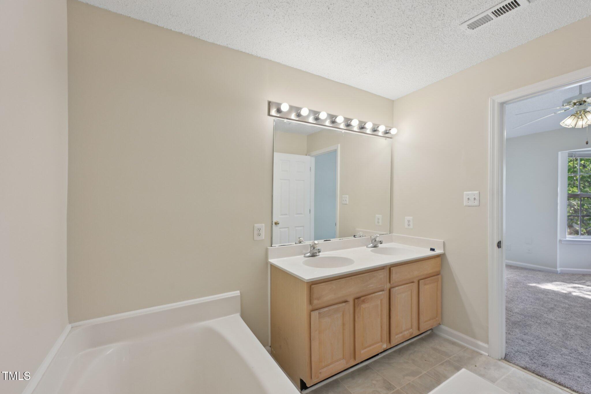 1031 Lake Moraine Place Raleigh, NC 27607 - Photo 23 of 33 a spacious bathroom with a double vanity sink a mirror and a bathtub