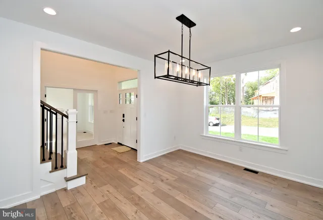 a view of a hallway with wooden floor and a kitchen space