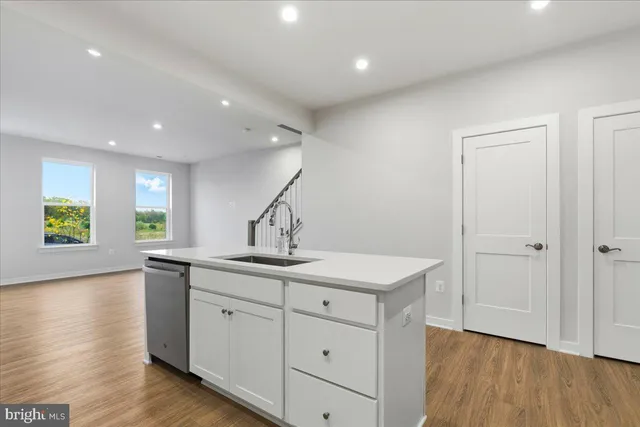 a kitchen with a sink stainless steel appliances and wooden floor