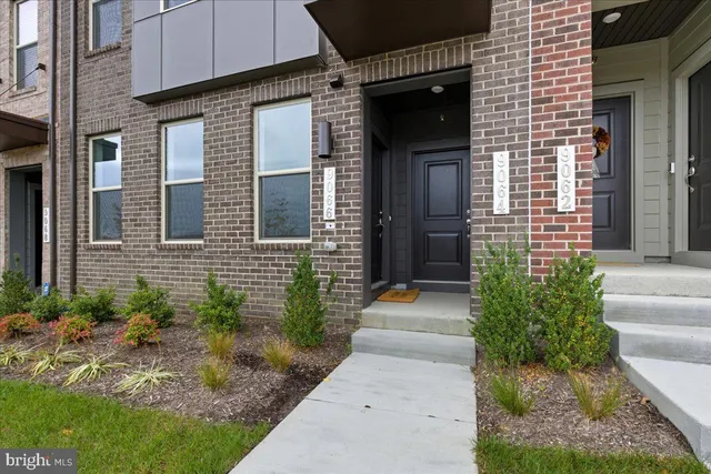 a view of brick house with a yard and plants