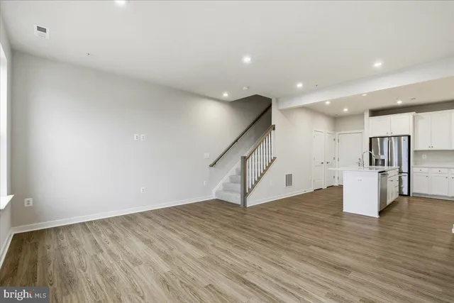a view of an empty room with wooden floor and staircase