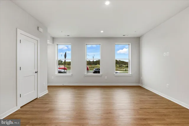 an empty room with wooden floor and windows