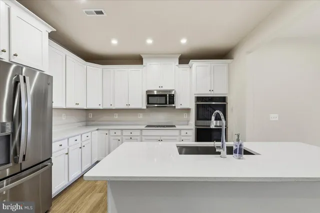 a kitchen with stainless steel appliances a refrigerator sink and white cabinets