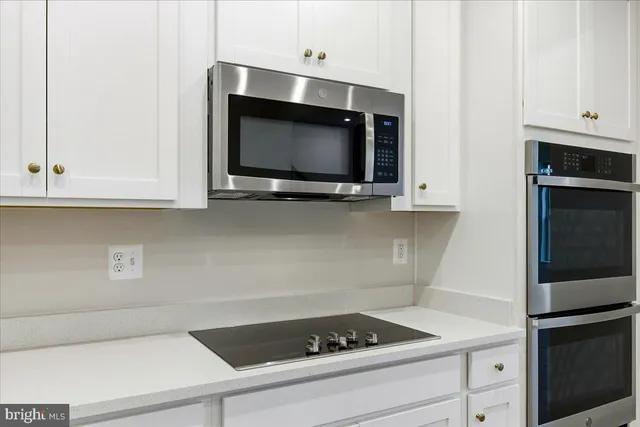 a kitchen with white cabinets and black appliances