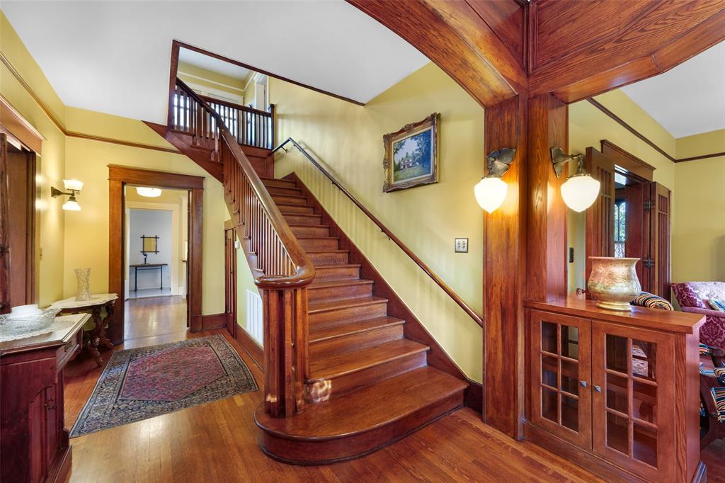 406 Griffith Avenue Terrell, TX 75160 - Photo 24 of 40 The property features hardwood floors, a grand wooden staircase with a banister, and wood trim throughout