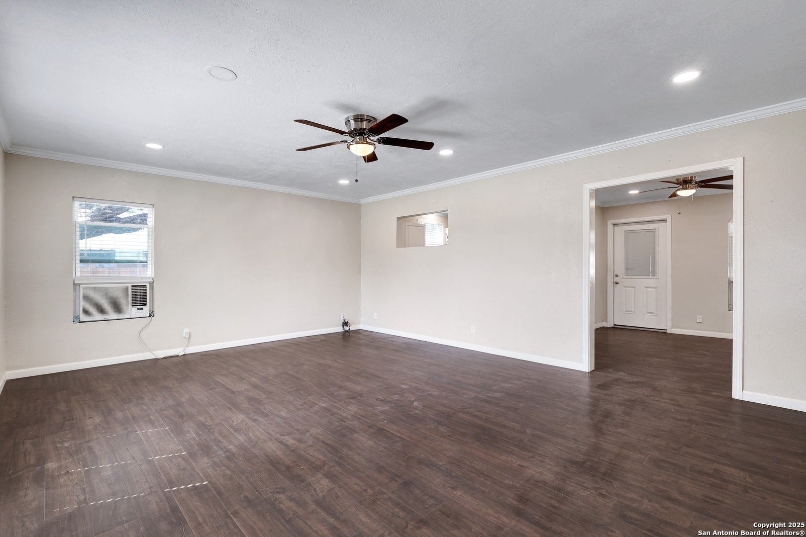 507 Hayden Avenue Devine, TX 78016 - Photo 6 of 26 a view of an empty room with a window and wooden floor