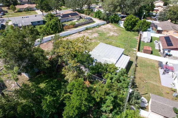 an aerial view of residential houses with outdoor space and trees all around