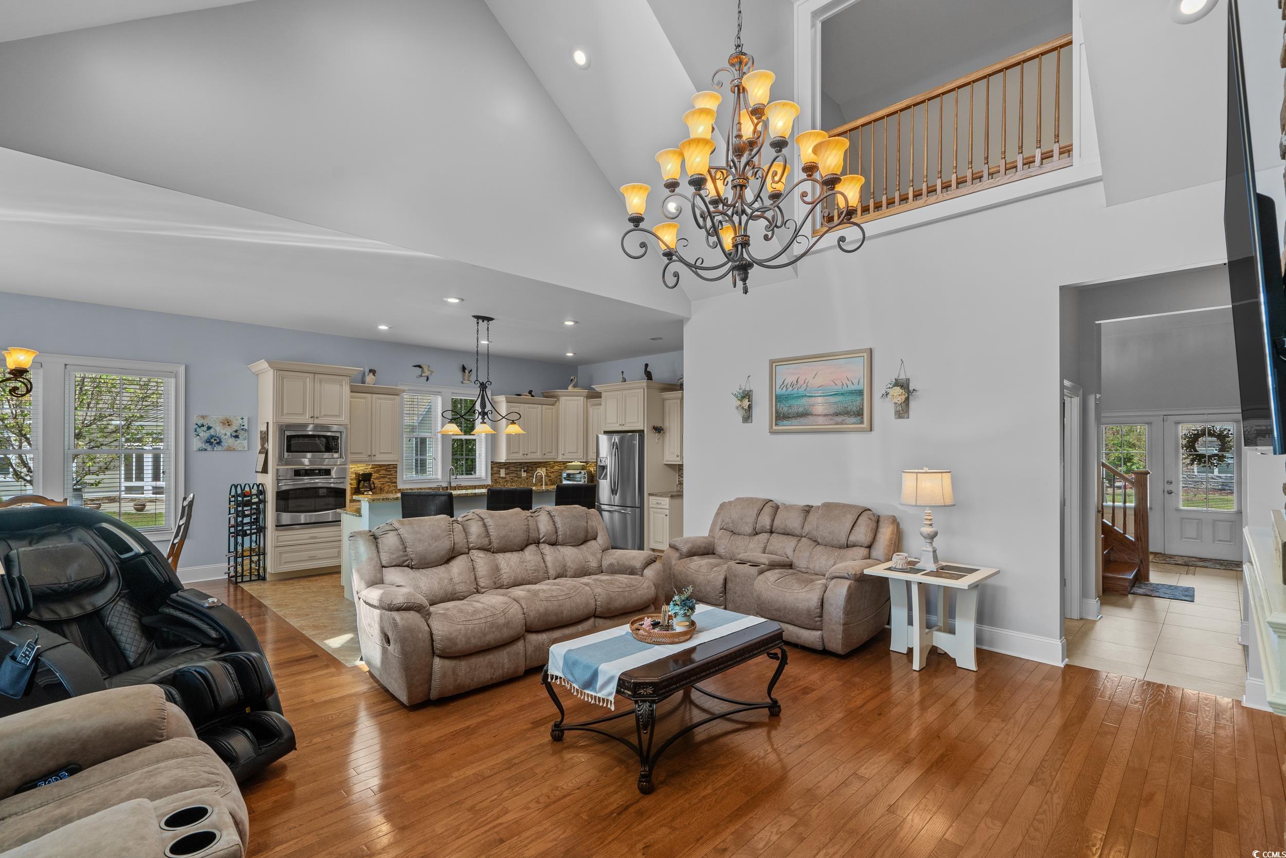 416 Seabury Lane Myrtle Beach, SC 29579 - Photo 8 of 39 Living room with light wood finished floors, a notable chandelier, a towering ceiling, and a fireplace