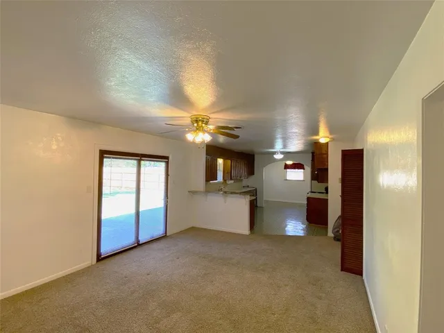 a view of an empty room and a kitchen