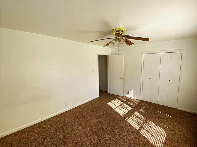 a view of a room with a ceiling fan and carpet