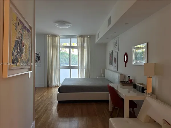 a bedroom with a bed wooden floor and window