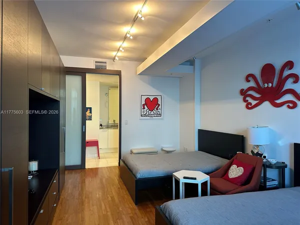 a view of an empty room with wooden floor and a window
