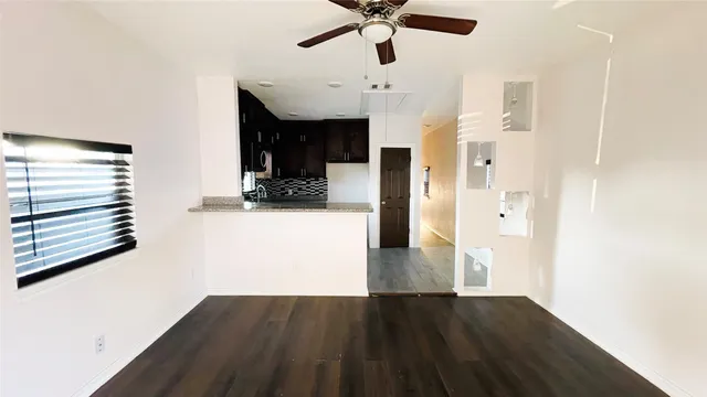 a view of a hallway with wooden floor and a ceiling fan